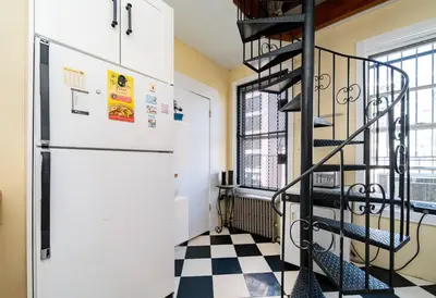 a black spiral staircase in a room with a checkered floor at Charming 3-Bedroom Apartment in Midtown West in New York
