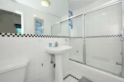 a white bathroom with a sink and a shower at Charming 3-Bedroom Apartment in Midtown West in New York