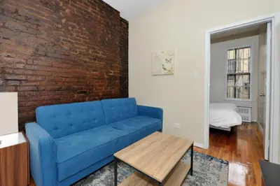 a blue couch in a living room with a brick wall at Charming 1BR in Murray Hill Kips Bay - Perfect for 2 in New York