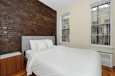 a bedroom with a large white bed with a brick wall at Charming 1BR in Murray Hill Kips Bay - Perfect for 2 in New York