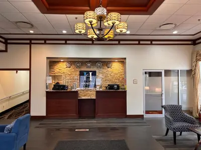 a lobby with a bar in a building with a chandelier at Hamden Hotel and Suites HAMDEN - NEW HAVEN in Hamden