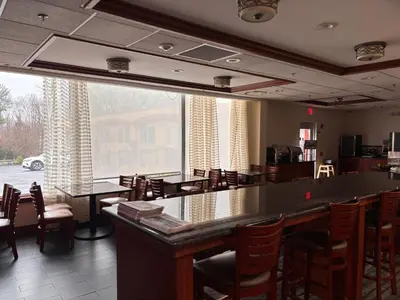 a large room with tables and chairs and a large window at Hamden Hotel and Suites HAMDEN - NEW HAVEN in Hamden