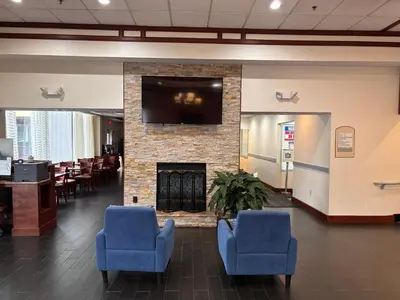 a lobby with two blue chairs and a fireplace at Hamden Hotel and Suites HAMDEN - NEW HAVEN in Hamden