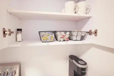 a kitchen shelf with cups and dishes on it at The Platinum Downtown Stamford Studio Getaway in Stamford