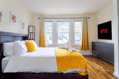 a bedroom with a large bed with a yellow blanket at Family Apt: 2BR FREE Parking Airprt City Links in Newark