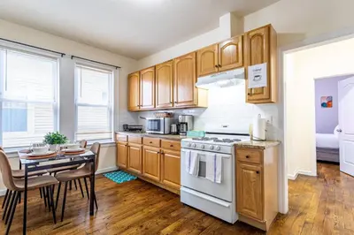 a kitchen with wooden cabinets and a table and a stove at Family Apt: 2BR FREE Parking Airprt City Links in Newark