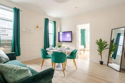 a living room with a table and green chairs at 6-Guest Jersey City Haven: Location-Comfort-Vibes in Jersey City