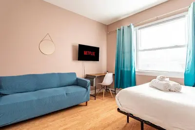 a living room with a blue couch and a bed at City Outside Serenity Inside: 2B1B NYC - 40 Min in Jersey City