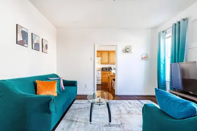 a living room with a blue couch and a tv at Family Urban: 2BR FREE Pkng Airport NYC Ease in Newark