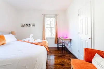 a white bedroom with a bed and a table at Family Urban: 2BR FREE Pkng Airport NYC Ease in Newark