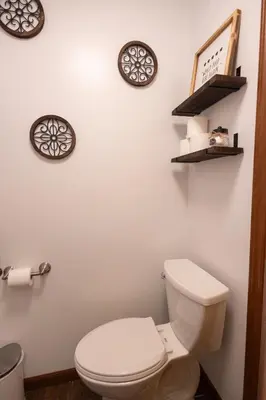 a bathroom with a toilet and three clocks on the wall at R&C Getaway in Greenville