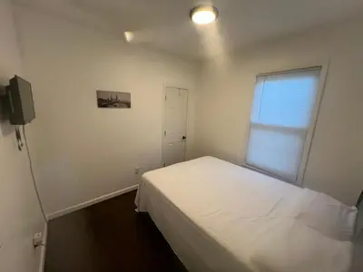 a small bedroom with a white bed and a window at Newly renovated furnished home in Newark