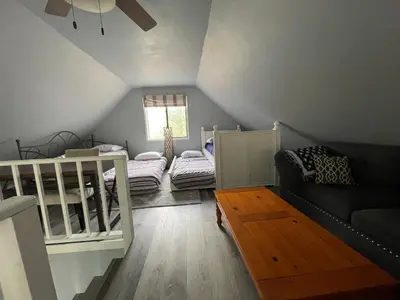 a attic room with two beds and a couch at Fully updated home with hot tub in amenity filled community in Lackawaxen