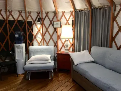 a room with a couch and a chair in a yurt at Modern Countryside Yurt Rental in Waterville, Upstate New York in Waterville