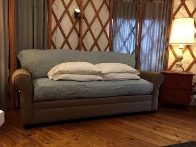 a couch with two pillows on it in a room at Modern Countryside Yurt Rental in Waterville, Upstate New York in Waterville