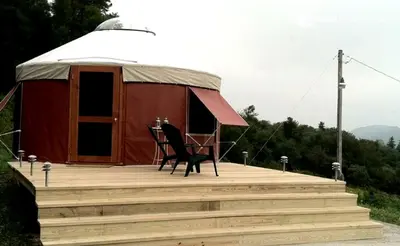 a yurt with a table and chairs on a wooden deck at Modern Countryside Yurt Rental in Waterville, Upstate New York in Waterville