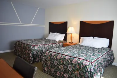 a hotel room with two beds and a table with a lamp at East Norwich Inn in East Norwich