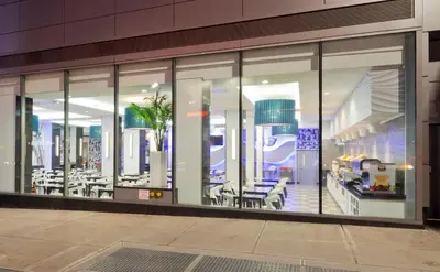 a large glass window of a building with tables and chairs at Riu Plaza New York Times Square in New York