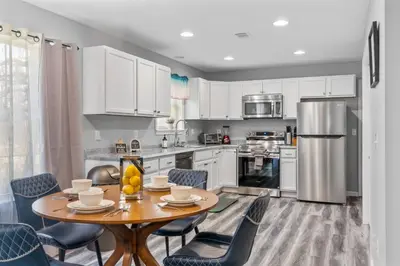 a kitchen with a wooden table and blue chairs at Emerald Lakes Poconos Retreat Game Room, Firepit & Sleeps 10 in Long Pond