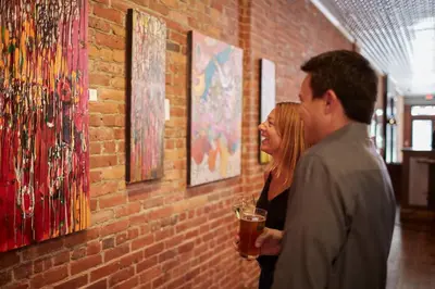 a man and a woman looking at art on a wall at Hotel on North in Pittsfield