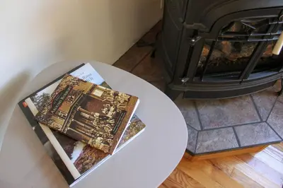 a stack of books sitting on a table next to a fireplace at Bellwood Cottage 8-14min to all Roxbury Wed Venues in Roxbury