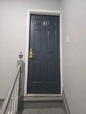a black door with a number on it next to stairs at favour family house in Newark