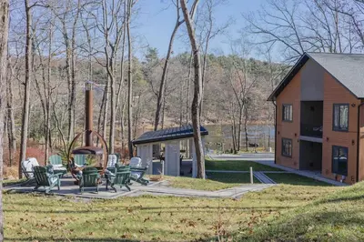 a group of chairs and a house with a fireplace at Luxury 6BR Mansion - Lakefront, Sauna, Hot Tub in Scotrun