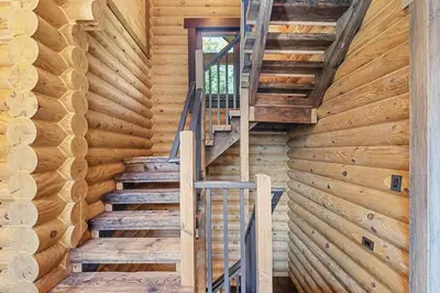 a staircase in a log cabin with wooden walls at Log House Chalet, Volleyball field, Sauna, Hot Tub in Henryville