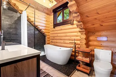 a bathroom with a toilet and a tub in a log cabin at Log House Chalet, Volleyball field, Sauna, Hot Tub in Henryville