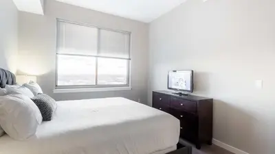 a bedroom with a white bed and a television at Modern Apartment In Harbor Point in South End