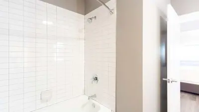 a white tiled bathroom with a bath tub at Modern Apartment In Harbor Point in South End