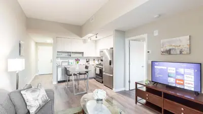 a living room with a couch and a tv and a kitchen at Modern Apartment In Harbor Point in South End
