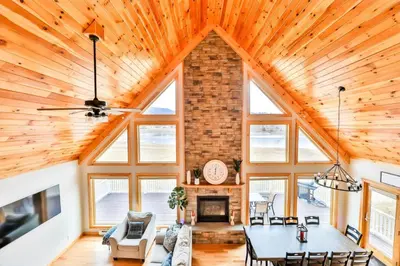 a living room with a vaulted ceiling and a fireplace at Lakeside Catskills Escape - Soak, Sip, Stargaze in Cairo