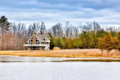 a house on the shore of a body of water at Lakeside Catskills Escape - Soak, Sip, Stargaze in Cairo