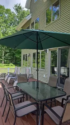 a table with chairs and an umbrella on a deck at Catskills retreat - ATV, Hot tub, hiking, fishing in Cairo