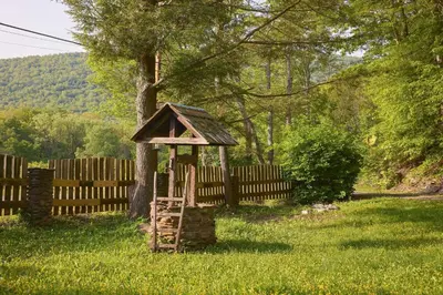 a bird house sitting in the grass next to a fence at 7 Mi to Belleayre Ski Mountain Getaway with Porch in Fleischmanns