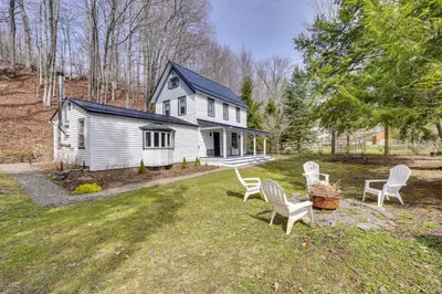a white house with white chairs in the yard at 7 Mi to Belleayre Ski Mountain Getaway with Porch in Fleischmanns