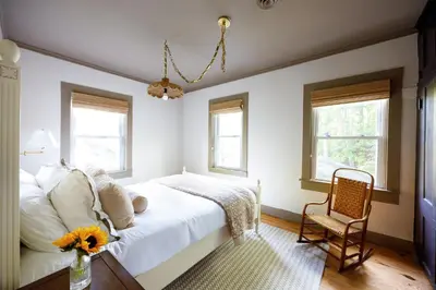 a bedroom with a bed and a chair and windows at 7 Mi to Belleayre Ski Mountain Getaway with Porch in Fleischmanns