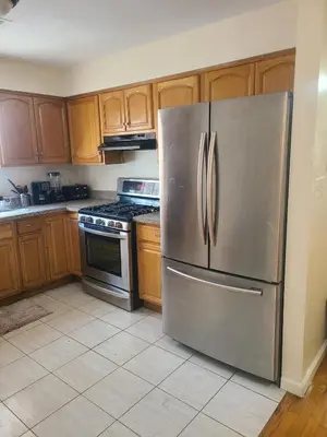 a stainless steel refrigerator in a kitchen with wooden cabinets at Amazing family house in Newark