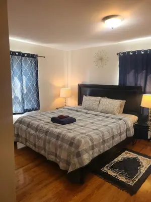 a bedroom with a bed with a blanket and a lamp at Amazing family house in Newark