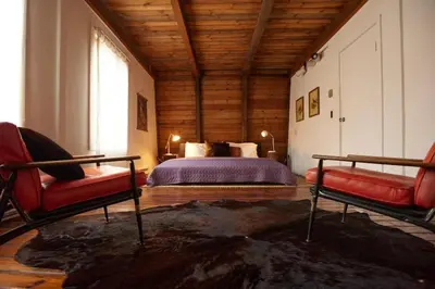 a bedroom with a bed and two red chairs at Peaceful Tree House Nestled Away in Hudson Valley, New York in Carmel Park Estates