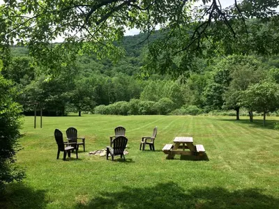 a group of chairs and a picnic table in a field at Homey Pet-Friendly Cabin Rental for Groups in the Catskills in Big Indian