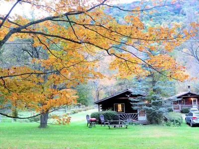 a cabin with a picnic table and chairs in the grass at Simple Cabin Camping for Families in the Catskills of Upstate New York in Big Indian