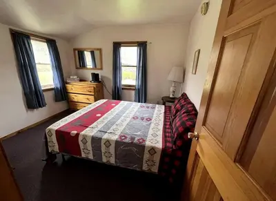 a bedroom with a bed and a dresser and windows at Simple Cabin Camping for Families in the Catskills of Upstate New York in Big Indian