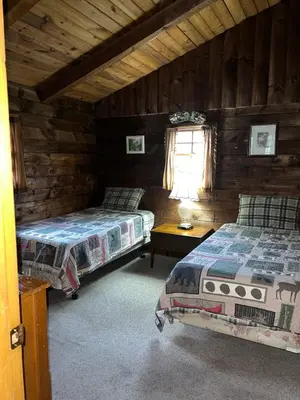 a bedroom with two beds in a log cabin at Simple Cabin Camping for Families in the Catskills of Upstate New York in Big Indian