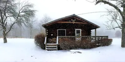 a small log cabin in the snow with snow at Rustic Cabin Rental for Groups near Woodstock, Upstate New York in Big Indian