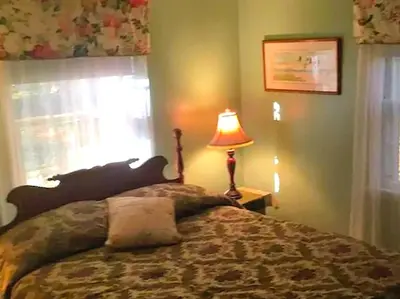 a bedroom with a bed with a lamp and a window at Peaceful and Pet-Friendly Cottage Rental on Picturesque Country Estate near Black Rock State Park, Connecticut in Watertown