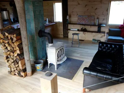 a living room with a woodburning stove in a cabin at Charming Cabin Getaway with a Wood-Burning Stove in Chesterfield, Massachusetts in Chesterfield