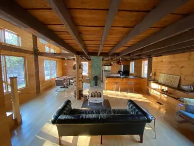 a large living room with a black leather couch at Charming Cabin Getaway with a Wood-Burning Stove in Chesterfield, Massachusetts in Chesterfield