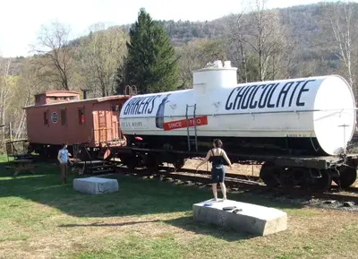 a person standing on a block in front of a train at Vintage Caboose Rental in Historic Small Town near Springfield, Massachusetts in Chester